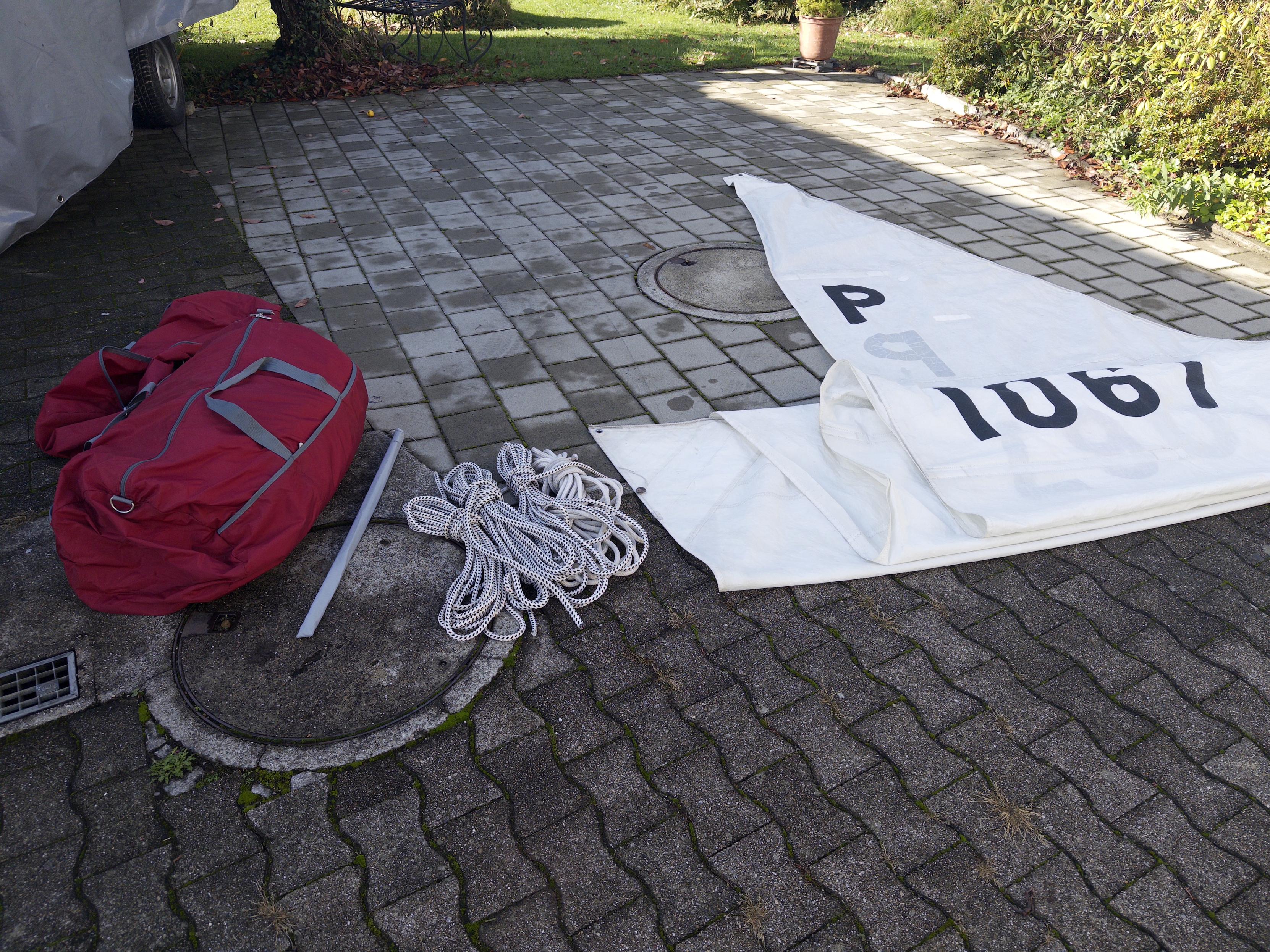 The mainsail on the floor next to a sail bag, and lines. Partially folded to be stowed away for the winter